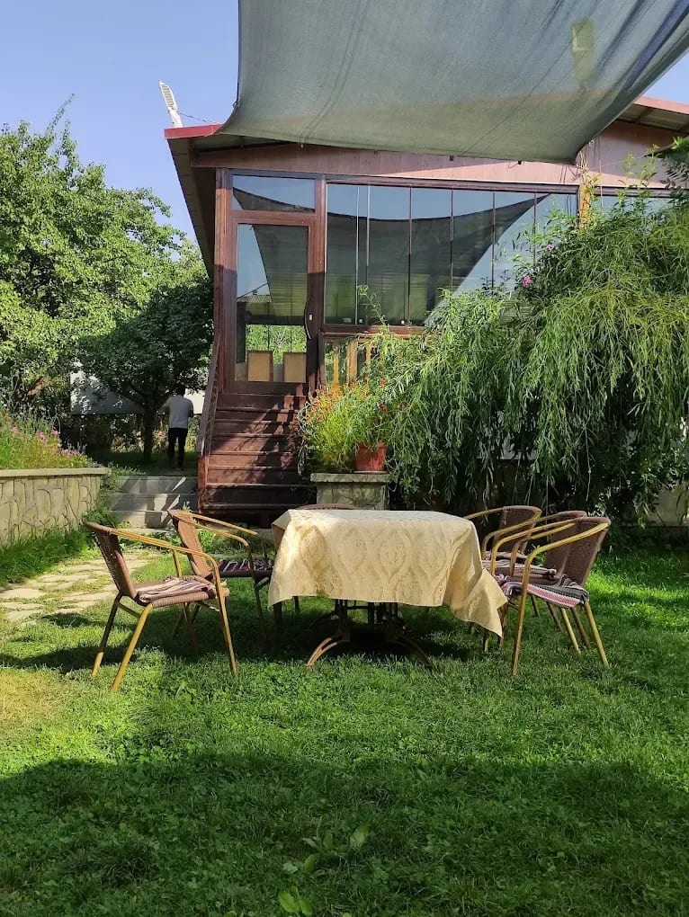 Altınsu bahçesinde ağaç dallarının yanında kurulu masa ve arka planda restoran salonu