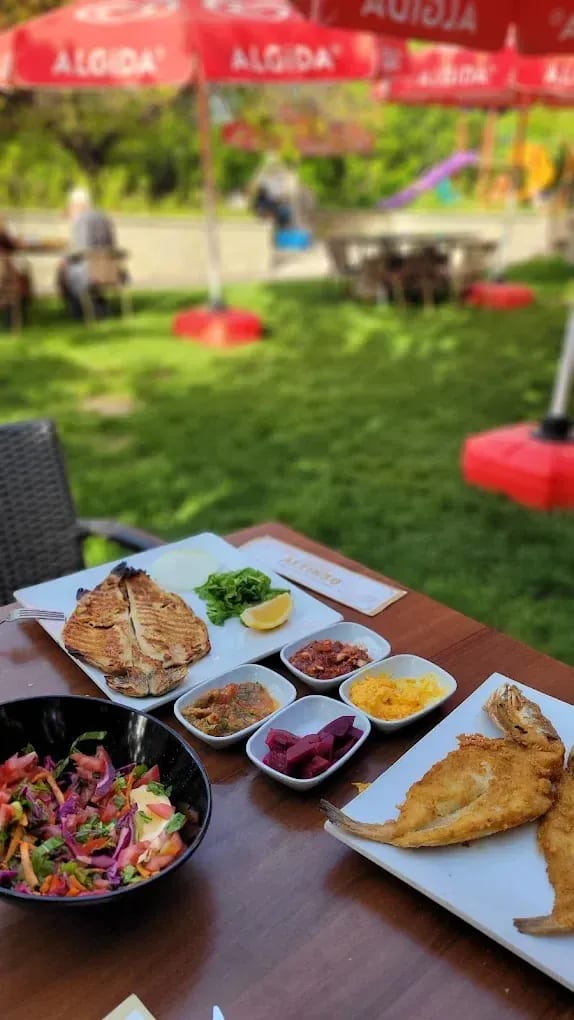 Altınsu bahçesinde balık tabakları, salata ve küçük eşlikçi tabaklarla kurulmuş sofra
