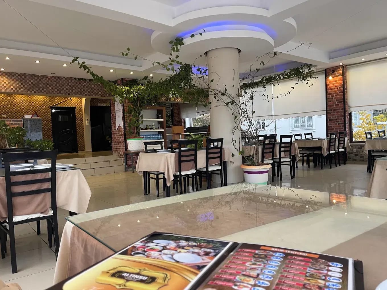 Altınsu restoranının salonunda örtülü masalar, sandalyeler ve bitkiler